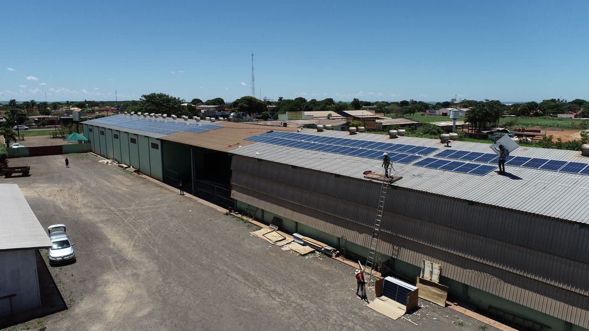 Galpão industrial com longa fileira de módulos fotovoltaicos na cobertura